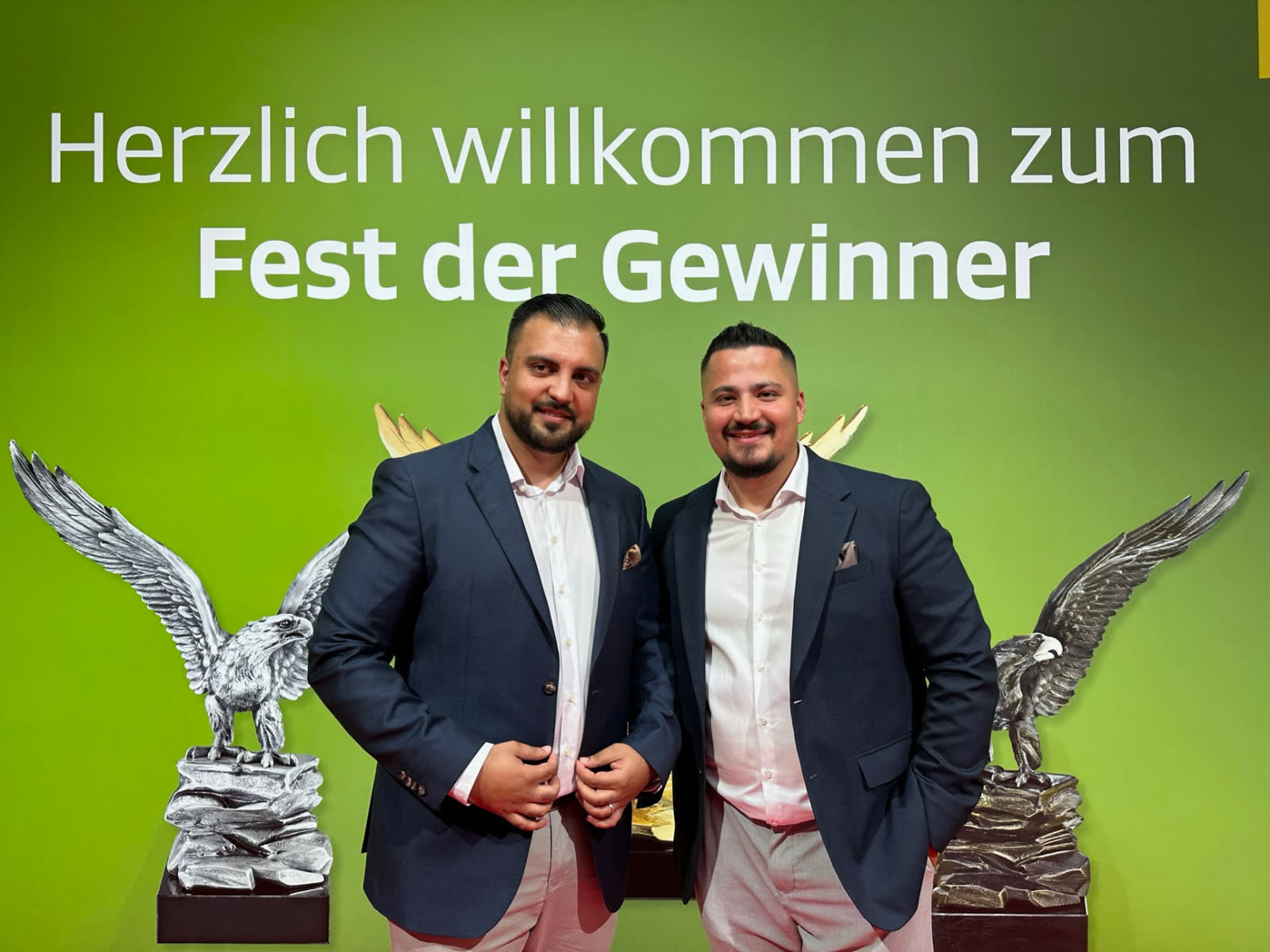Farshad Sahab mit Kollegen vor einer Wand mit der Aufschrift Fest der Gewinner
