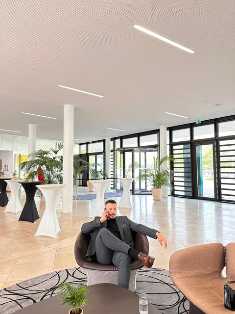 Farshad Sahab im Anzug in einer hellen Bürolobby während eines Telefonats