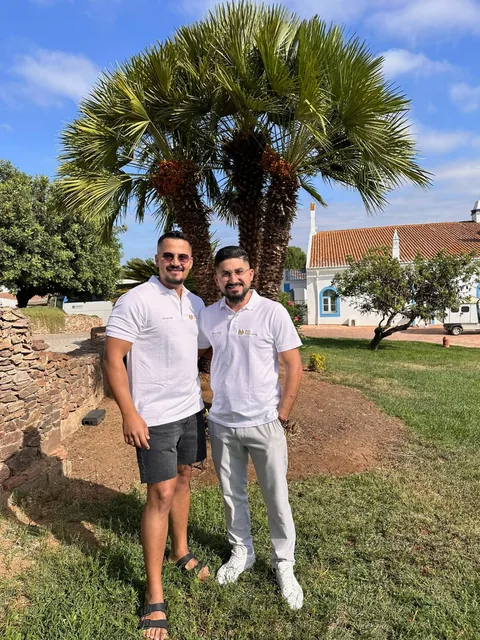Farshad Sahab mit einem Kollegen unter einer Palme in einer Ferienanlage